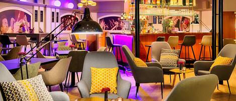 Un espace bar moderne, doté de sièges, d’un comptoir et d’une variété de bouteilles et de verres.