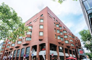 Un hotel de ladrillo rojo con varios pisos y un letrero llamativo que dice 'Leonardo Hotel'.