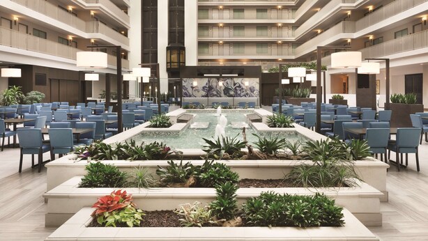 A hotel atrium with a central fountain, multiple dining areas, and a modern architectural design. - Embassy Suites by Hilton Brea North Orange County (Brea)
