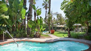 A swimming pool surrounded by lush greenery and palm trees. - Embassy Suites by Hilton Brea North Orange County (Brea)