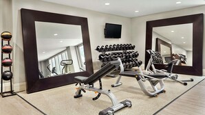 A gym with exercise equipment, a mirror, and a TV on the wall. - Embassy Suites by Hilton Brea North Orange County (Brea)