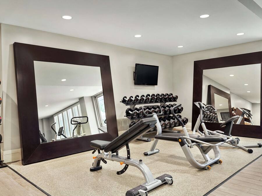Un gimnasio con equipo de ejercicio, un espejo y un televisor en la pared.