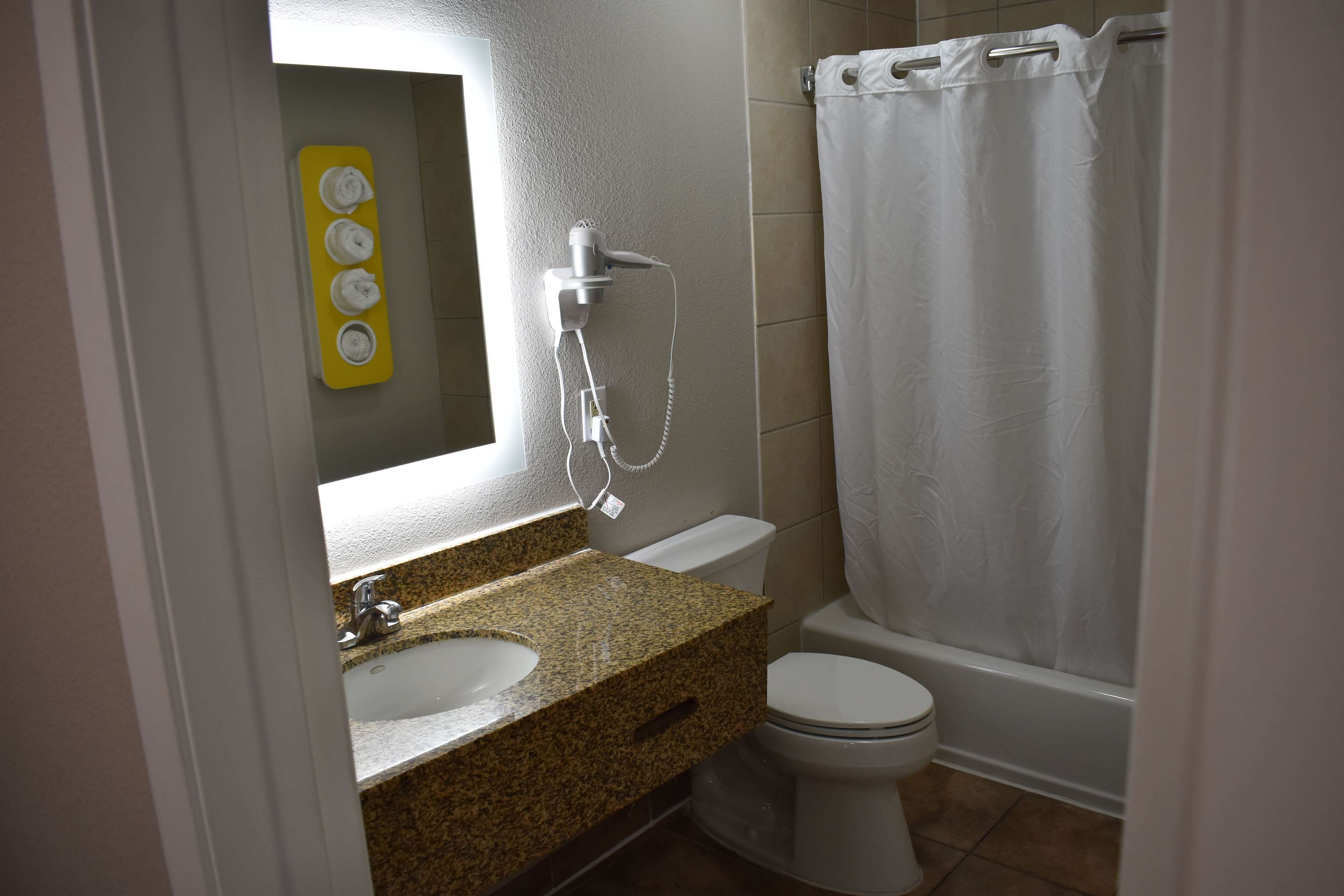 A bathroom with a granite countertop, a white sink, a toilet, and a shower curtain.