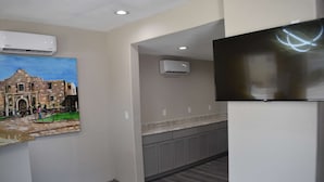 Una cocina moderna con armarios grises, horno empotrado y televisor de pantalla plana en la pared.