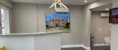 Un interior moderno con una pared de piedra, un cuadro de un edificio histórico, una lámpara de techo original y una silla verde.