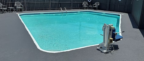 A swimming pool with a lifeguard chair and a pool lift.