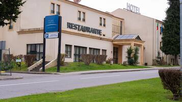 A hotel with a restaurant on the ground floor, a sign indicating reserved parking for hotel guests, and a satellite dish on the roof.
