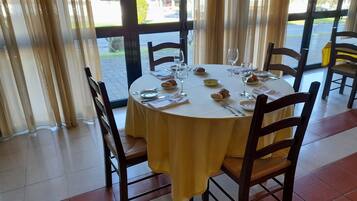 A round dining table with a yellow tablecloth, surrounded by wooden chairs.