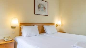 A hotel room with a bed, two bedside lamps, a nightstand with a phone, and a framed picture on the wall.