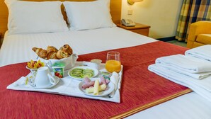A hotel room with a neatly made bed, a tray with breakfast items, and a bedside table with a lamp and phone. - Flag Hotel Guimaraes Fafe (Fafe)