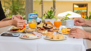 A breakfast table with various food items, a juice box, and a mobile phone. - Nobile Suites Excelsior Asuncion (Asunción)