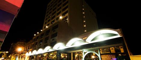 A multi-story hotel with a modern design, featuring a prominent entrance with a curved roof and large windows.