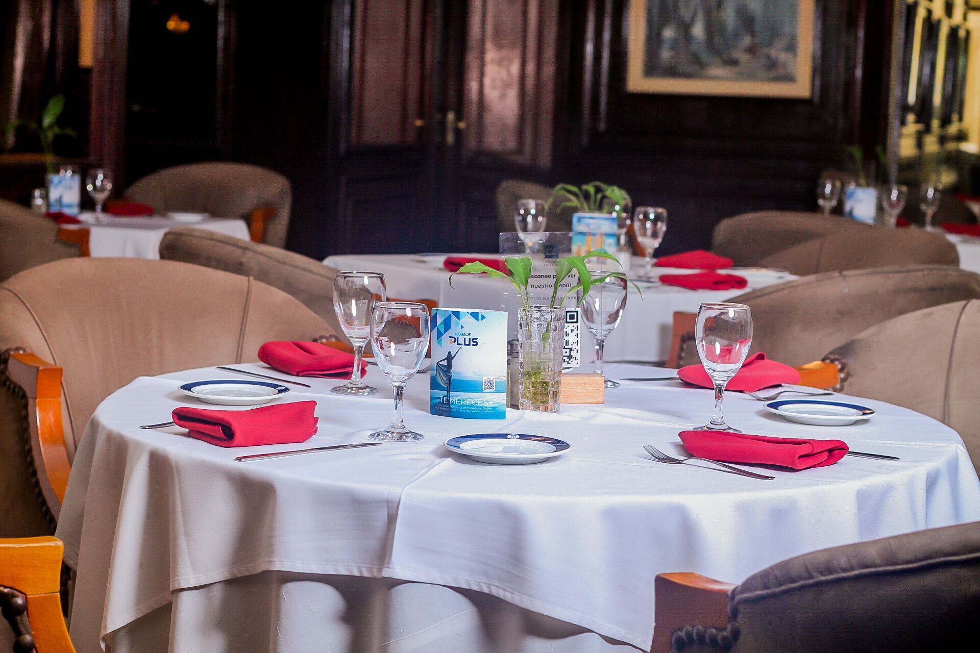 A dining table set with plates, cutlery, and glasses, with a QR code and a promotional sign on the table.