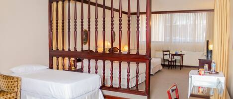Ein Hotelzimmer mit einem großen Bett, einer Couch, einem Schreibtisch mit Stuhl und einem Fernseher.