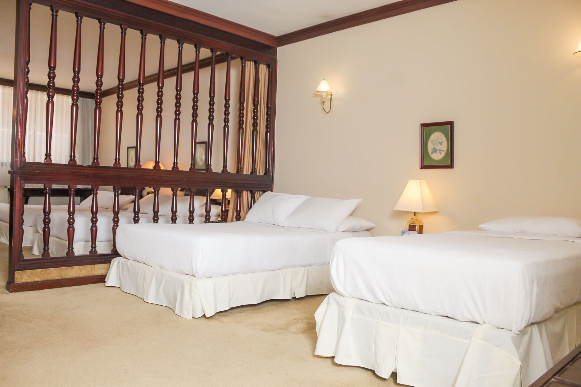 Habitación de hotel con dos camas, una escalera de madera, una lámpara de pared y un cuadro enmarcado.