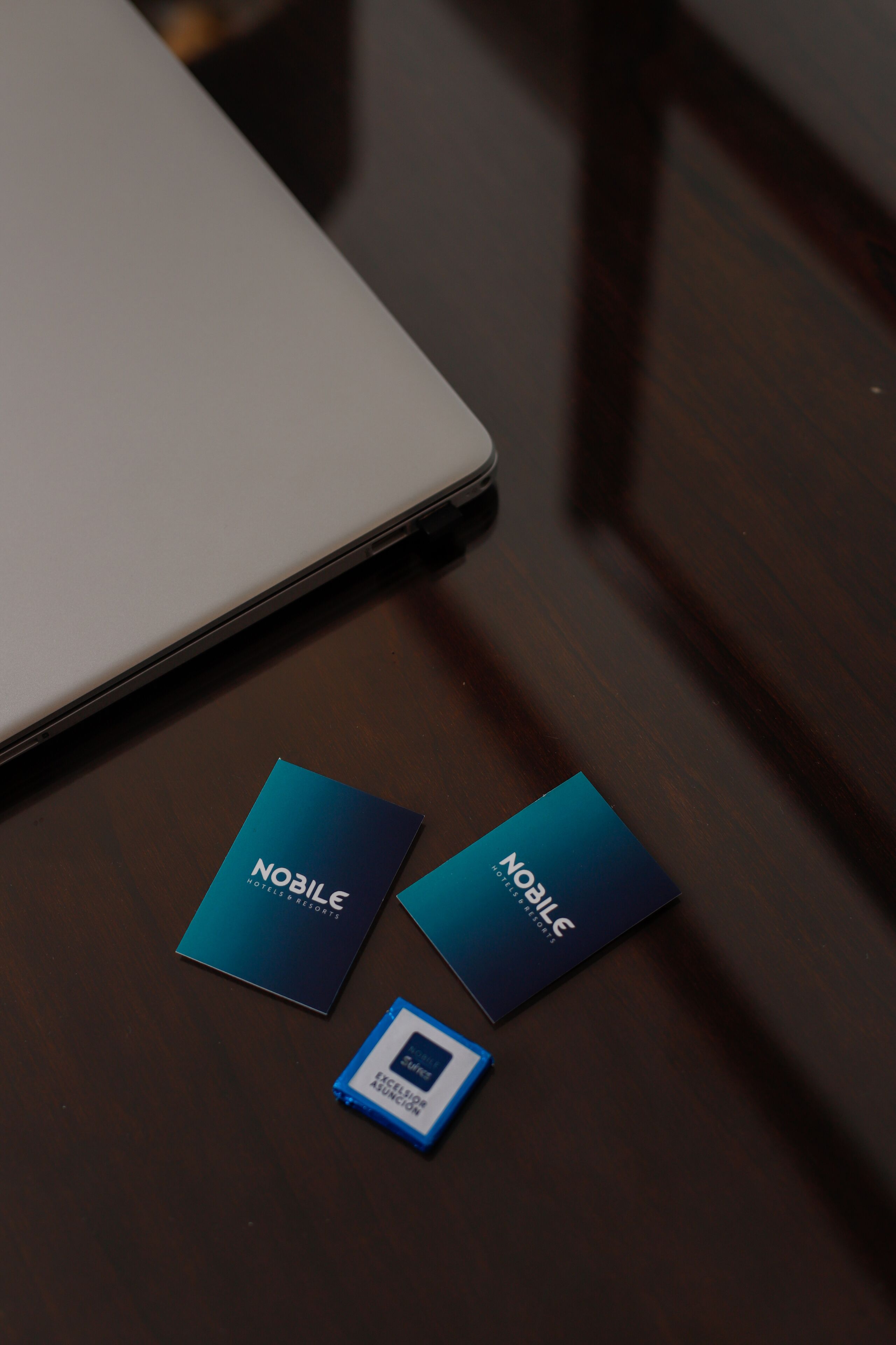A laptop and two business cards on a wooden surface.