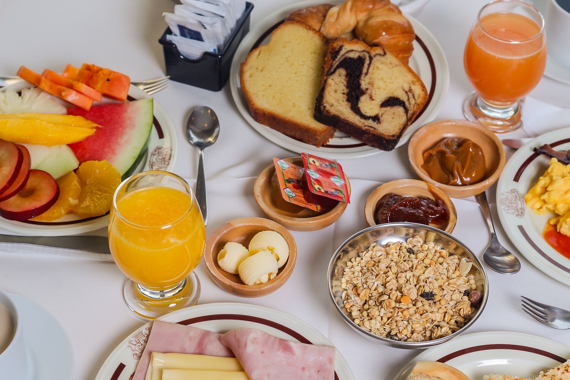 A breakfast table with various food items including fruits, bread, and beverages.