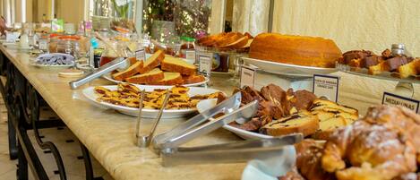 A buffet with various food items including bread, pastries, and cakes.