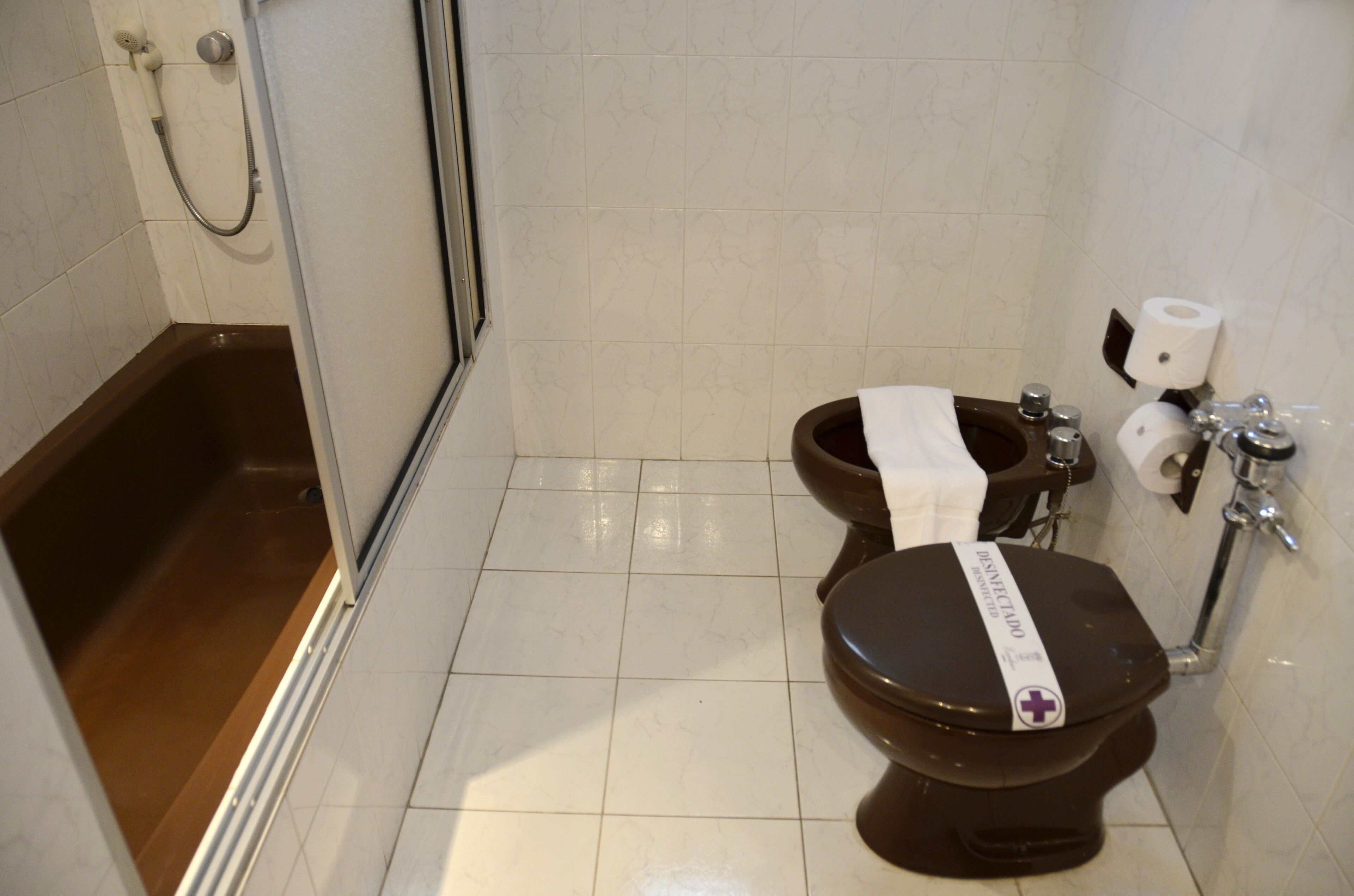 A bathroom with a bathtub, two toilets, and a shower.