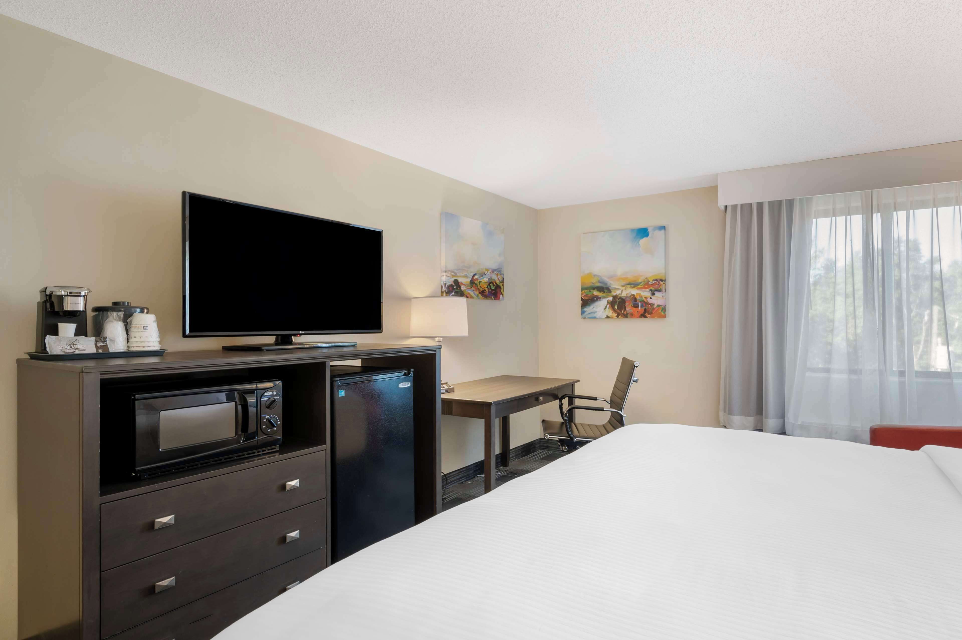 A hotel room with a bed, a desk, a television, a microwave, and a coffee maker.