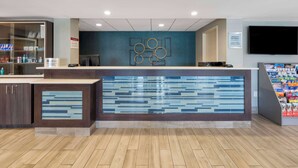 Un espace d’accueil au design moderne, comprenant un mur bleu orné de motifs géométriques, un comptoir d’accueil et un écran de télévision.
