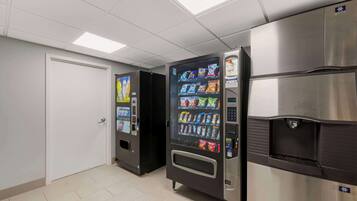 A vending machine and a refrigerator in a hallway.