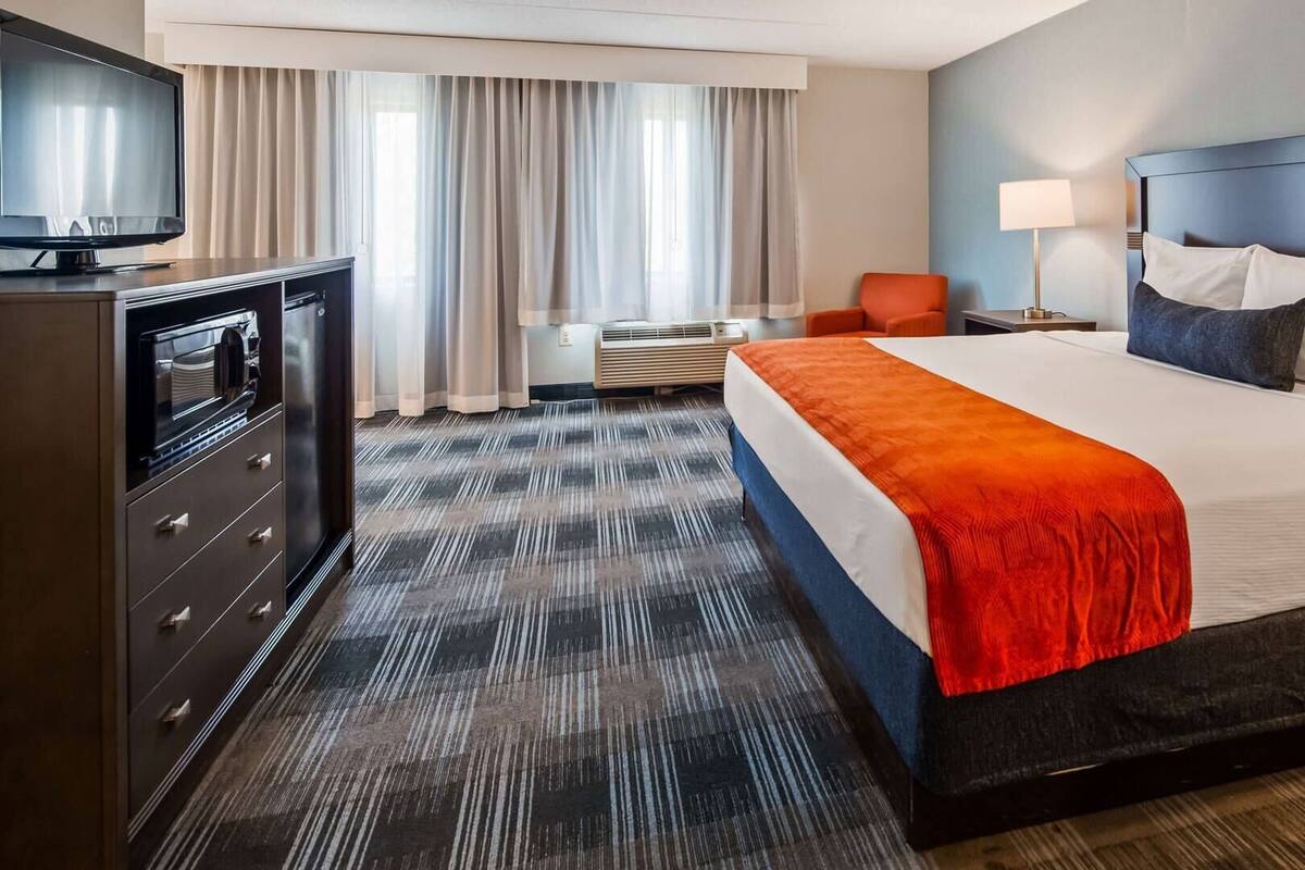 Een hotelkamer met een bed, een televisie, een bureau en een stoel.