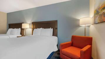 A hotel room with two beds, a red armchair, and a painting on the wall.