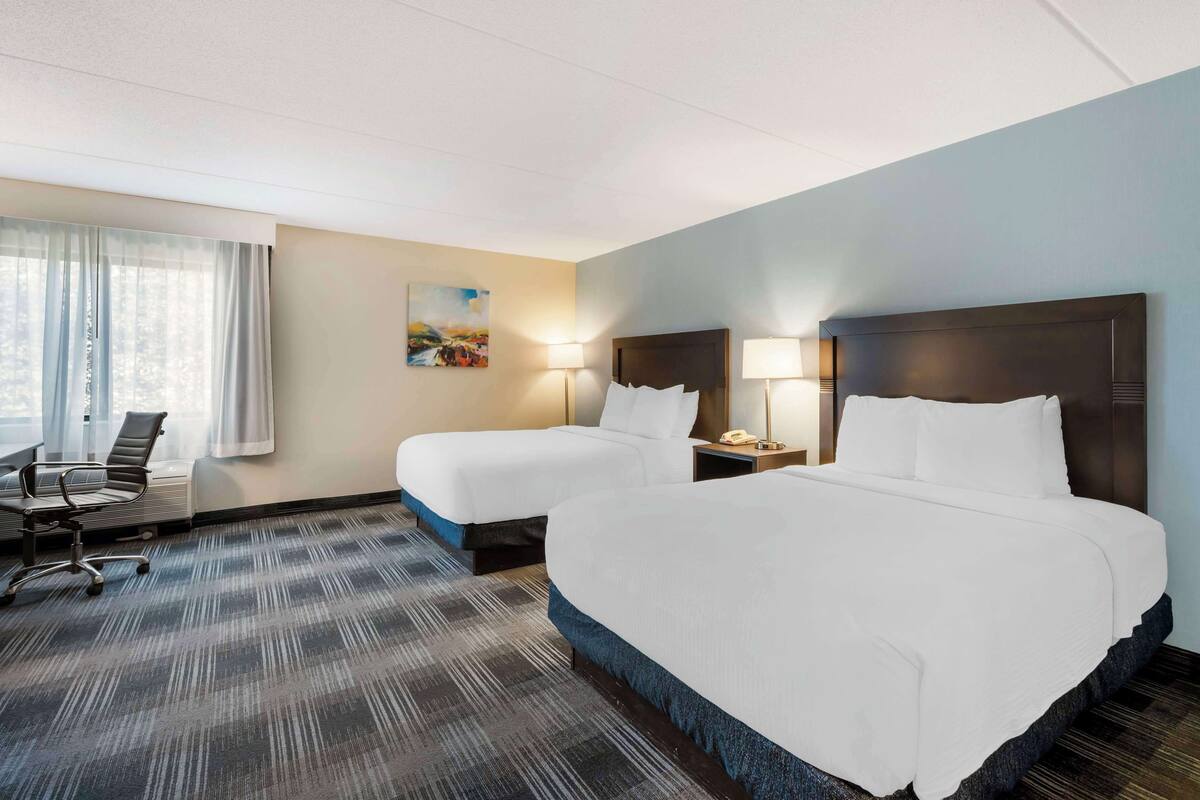Een hotelkamer met twee bedden, een bureau en een stoel.