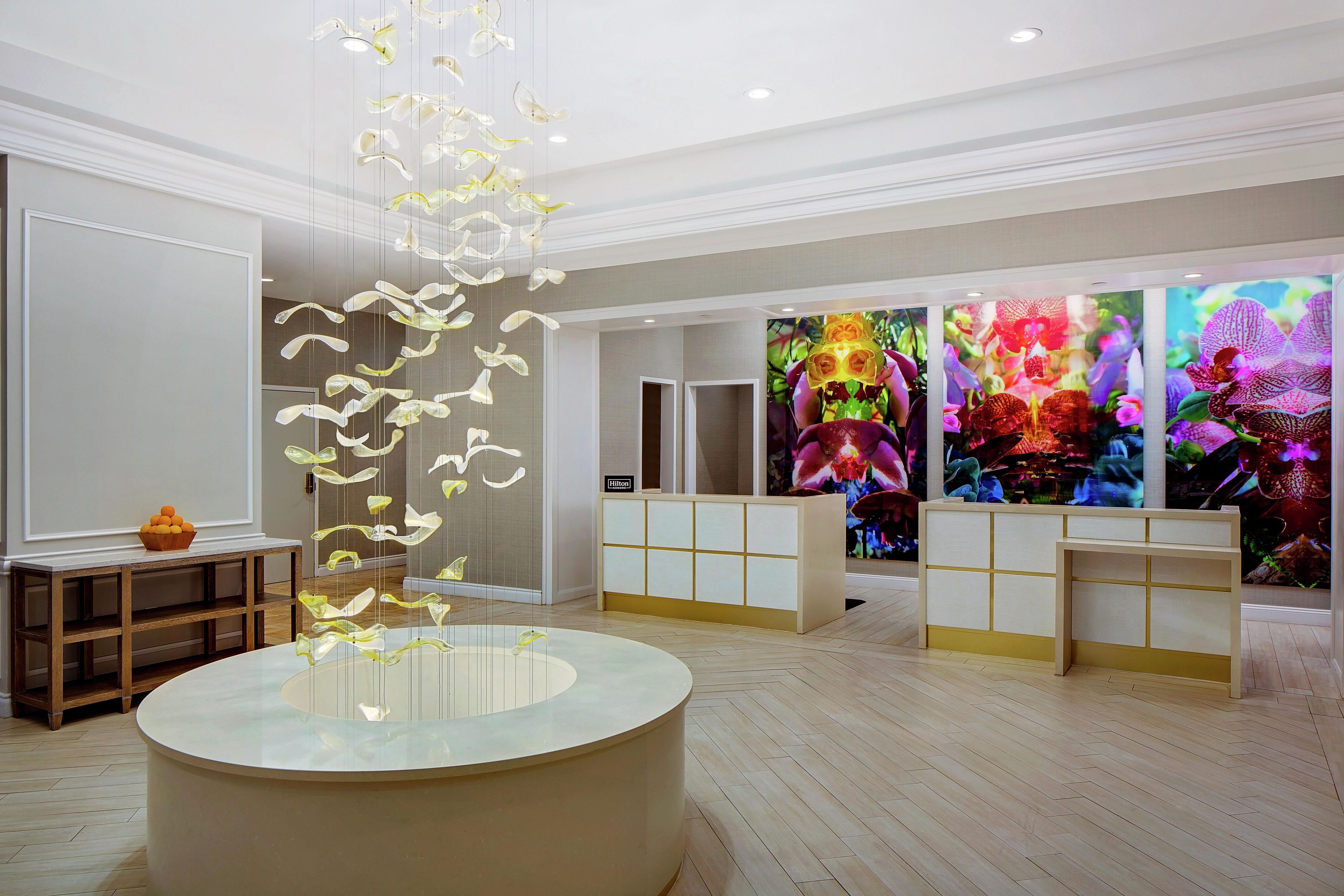A hotel lobby with a reception desk, a large glass sculpture, and vibrant artwork on the walls.