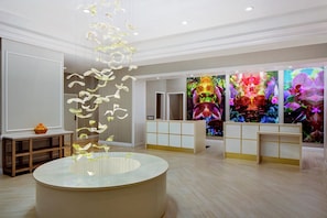A hotel lobby with a reception desk, a large glass sculpture, and vibrant artwork on the walls. - Hilton Ocala (Ocala)