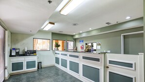 A reception area with a coffee machine, a trash bin, and a bulletin board. - Buena Vista Inn (Anaheim)