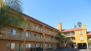 A multi-story motel with a red-tiled roof, balconies, and a parking lot. - Buena Vista Inn (Anaheim)