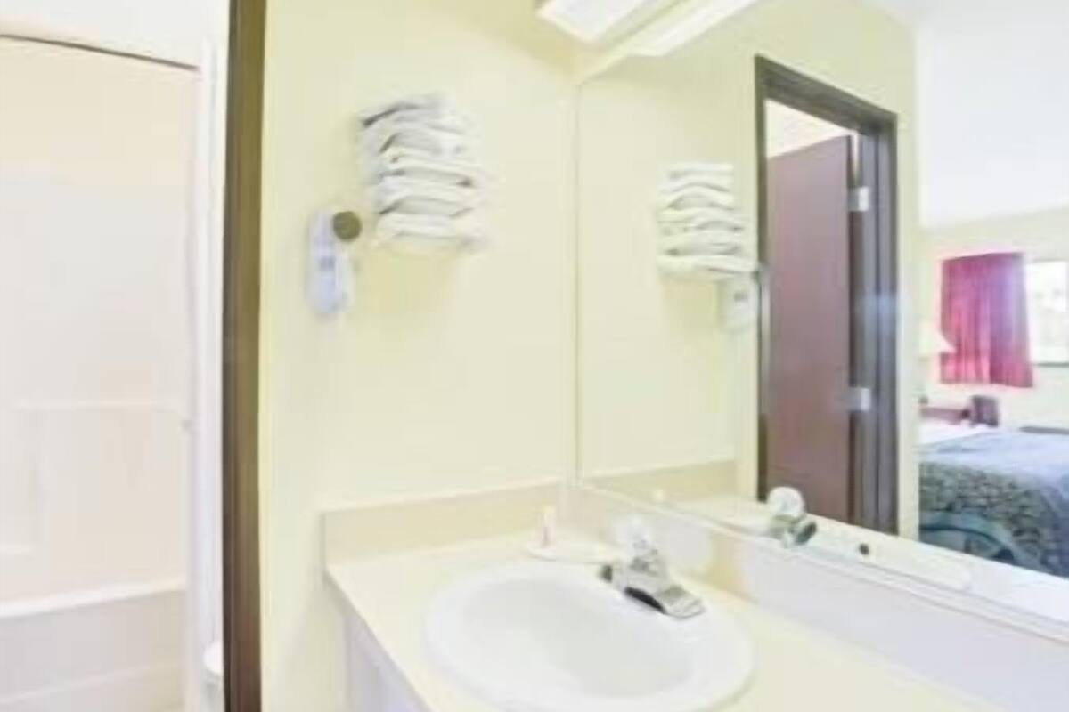 A bathroom with a white sink, a mirror, and a towel rack.