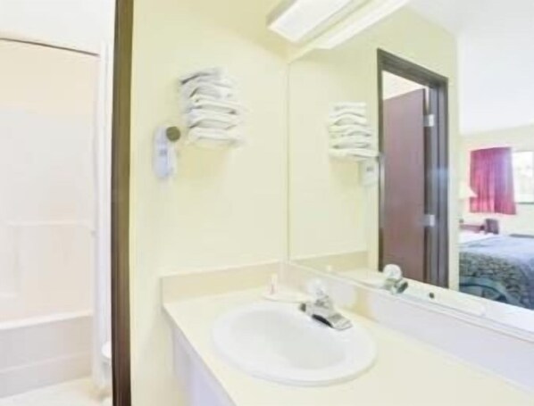 A bathroom with a white sink, a mirror, and a towel rack. - Days Inn by Wyndham Athens (Athens)