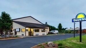Ein Days Inn Hotel mit schlichter, einstöckiger Bauweise, überdachten Parkplätzen und einem gepflegten Rasen.
