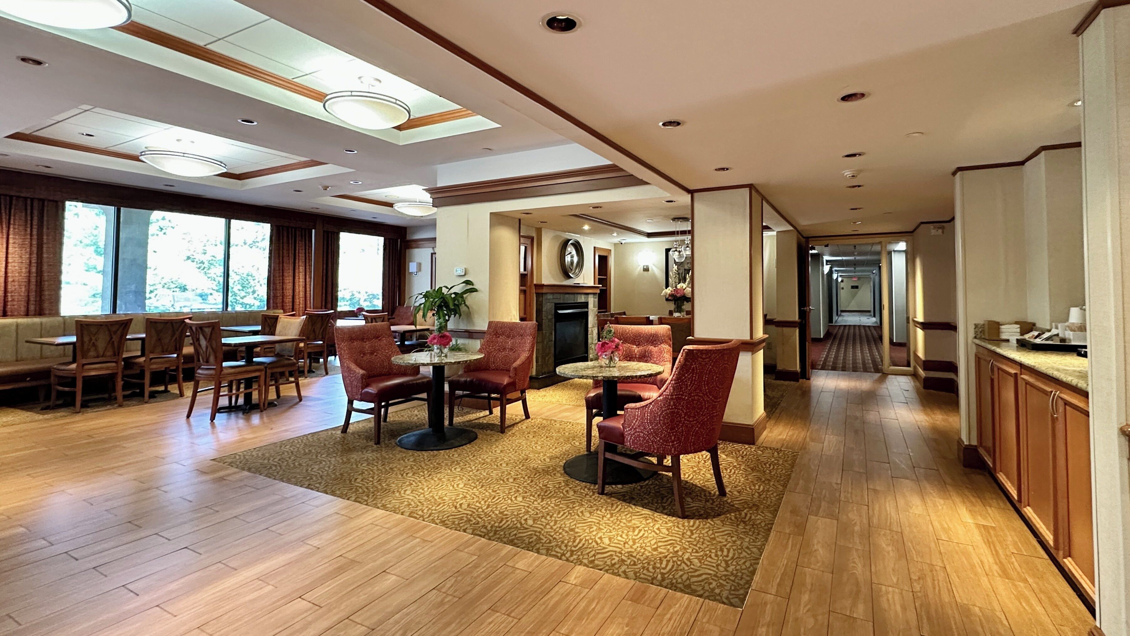 Un vestíbulo de hotel con zona de comedor, arreglos de asientos y chimenea.