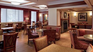 A hotel lobby with multiple seating areas, including a fireplace, tables, and chairs. - Long Creek Hotel by IHG (South Portland)