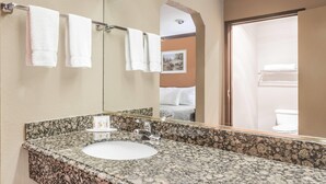 A bathroom with a granite countertop sink, a large mirror, and a towel rack with three towels. - Days Inn by Wyndham Bishop (Bishop)