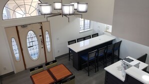 A modern kitchen with a central island, a dining area with a long table and chairs, and a small bar area. - Days Inn by Wyndham Bishop (Bishop)