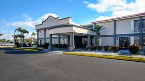 A modern hotel with a covered entrance, palm trees, and a clear blue sky.