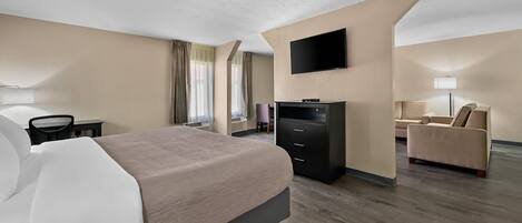 A modern hotel room with a large bed, a flat-screen TV, a desk, and a sofa.