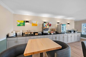 Een moderne keuken met een eethoek, voorzien van een koelkast, broodrooster en koffiezetapparaat.