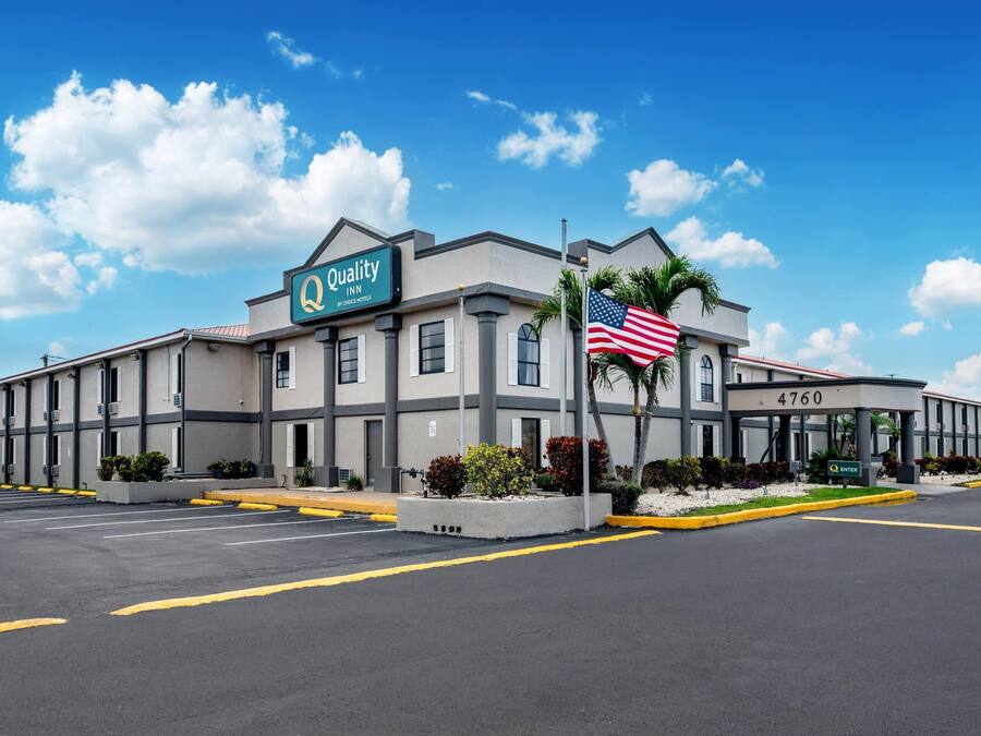 A Quality Inn hotel with a sign, American flag, and a parking lot.