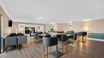 Een ruime vergaderzaal met moderne meubels en een keuken in de achtergrond.