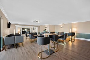 Een ruime vergaderzaal met moderne meubels en een keuken in de achtergrond.