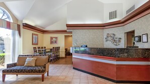 A hotel lobby with a reception desk, a sofa, a dining area, and framed artwork on the walls. - Best Western Plus Inn at Valley View (Roanoke)