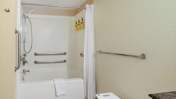 A bathroom with a bathtub, a shower, a towel rack, and a handrail.