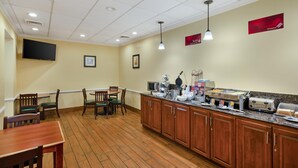 A restaurant with wooden flooring, a counter with food service equipment, and a television mounted on the wall.