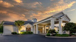 A hotel with a covered entrance, a large tree, and a well-maintained lawn. - Best Western Plus Inn at Valley View (Roanoke)